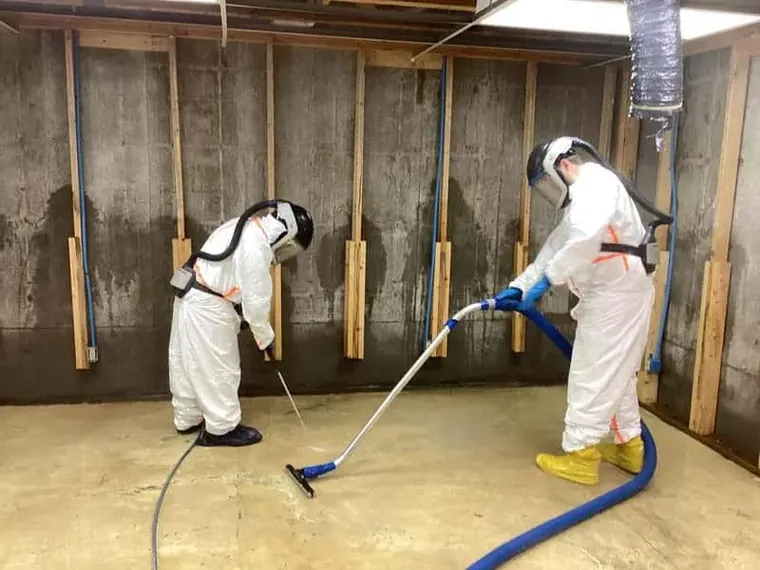 A technician in protective gear cleaning up after a water loss