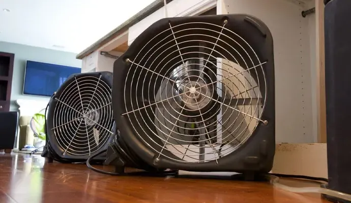 Air movers drying a water damaged room
